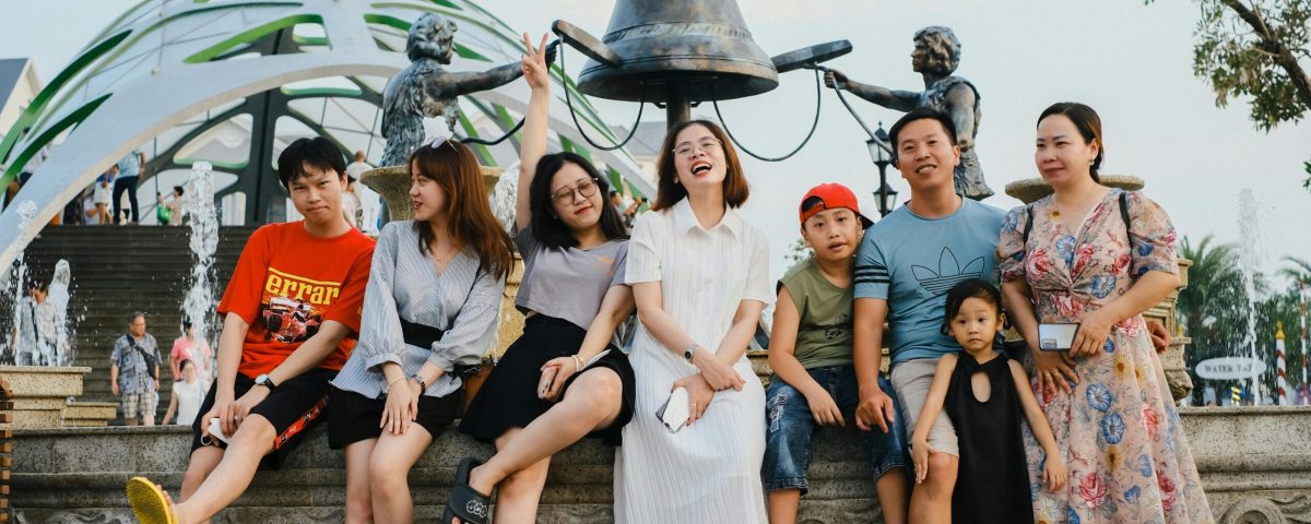 A joyful group posing at a sculpture fountain in a lively outdoor setting.